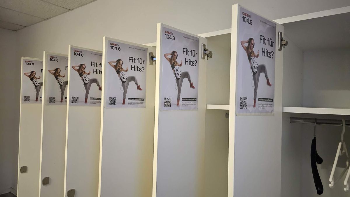 Geöffnete Spinde in einer Umkleide, innen an jeder Tür ein Werbeplakat mit QR-Code